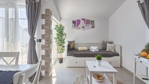 Une chambre moderne et bien éclairée, avec un lit, une petite table, une chaise et une plante en pot.