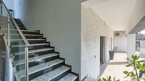 Un escalier moderne avec des rampes en verre menant à un balcon agrémenté d’un pot de fleurs.
