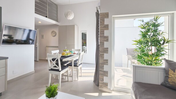 Une cuisine moderne avec un coin repas, un téléviseur et un escalier menant à un niveau supérieur.