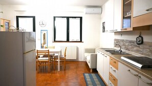 Una cocina compacta con refrigerador, mesa, sillas, lavamanos y armarios.
