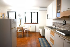 Une cuisine de taille réduite comprenant un réfrigérateur, une table à manger, des chaises, un évier et des placards.