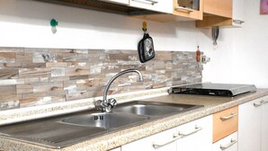Una cocina con encimera de granito, pileta de acero inoxidable y muebles altos blancos.