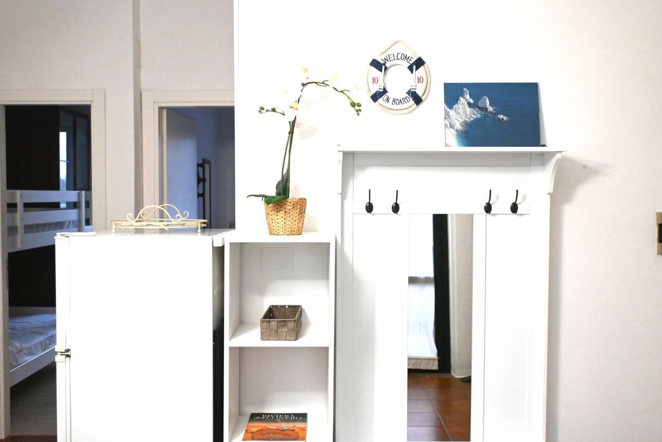 Ein Zimmer mit einem Etagenbett, einem weißen Schrank mit Regalen, einem Korbwäscheschrank, einem Willkommensschild und einem gerahmten Bild.