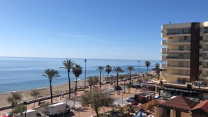 A coastal view with a beach, palm trees, and a building with a sign reading "HELADERIA 900 ITALIANA". - Nice apartment, in front of the beach. (Fuengirola)