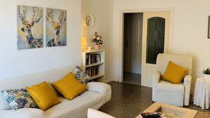 A living room with a sofa, armchair, coffee table, and a bookshelf. - Nice apartment, in front of the beach. (Fuengirola)