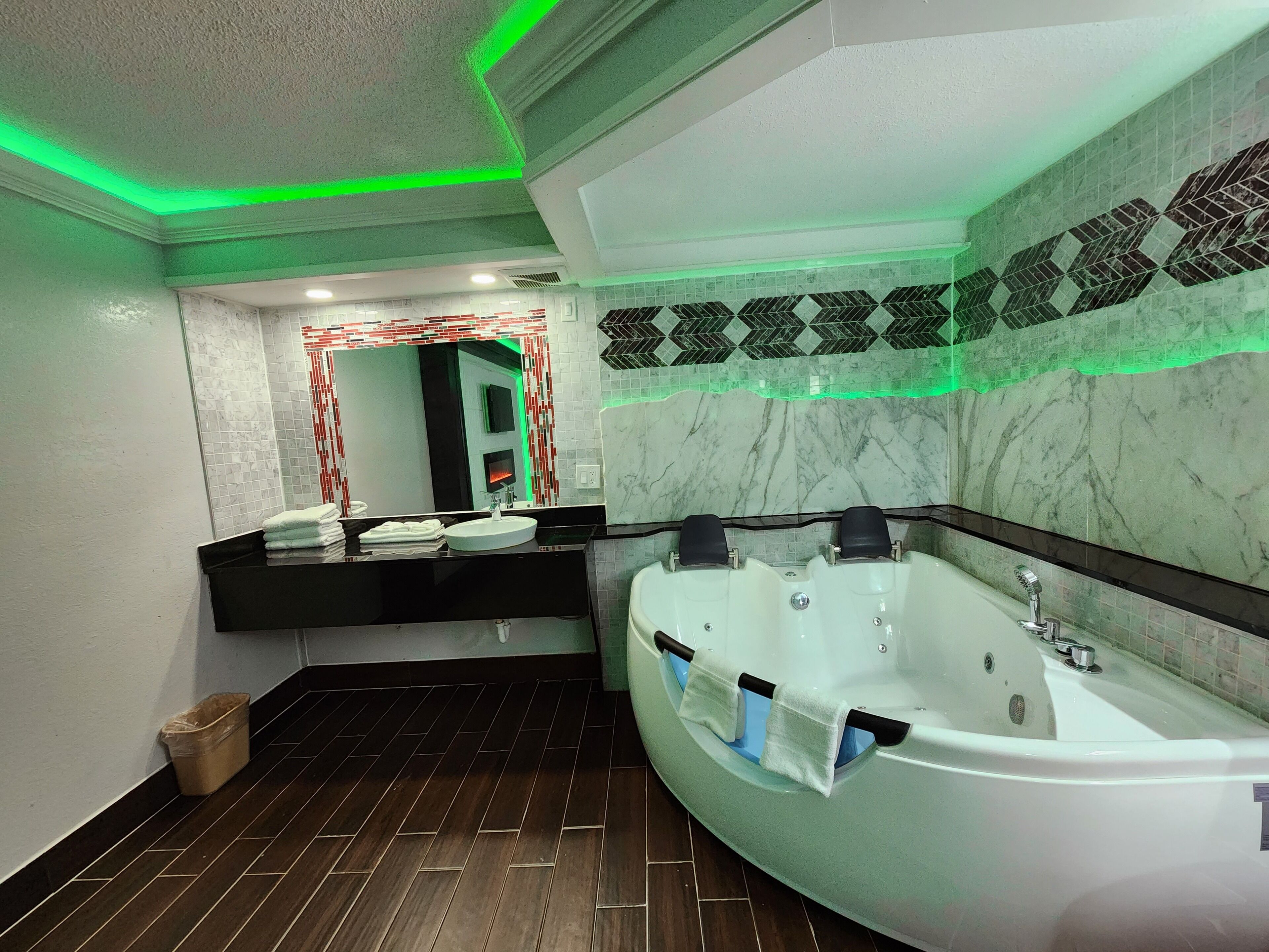 A modern bathroom with a large bathtub, a vanity with a mirror, and a tiled backsplash.