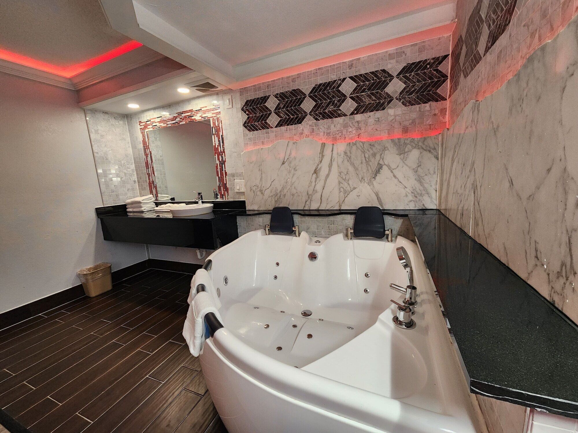 A modern bathroom with a large bathtub, a black countertop, and a mirror above the sink.