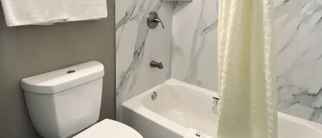 Un baño con inodoro, bañera y cortina de ducha.