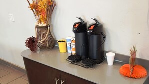 A kitchen counter with a coffee maker, a sugar container, and a decorative orange flower.