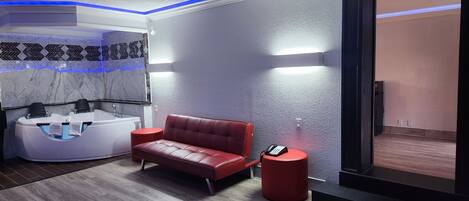 A modern spa room with a red leather sofa, a white massage chair, and a red stool.