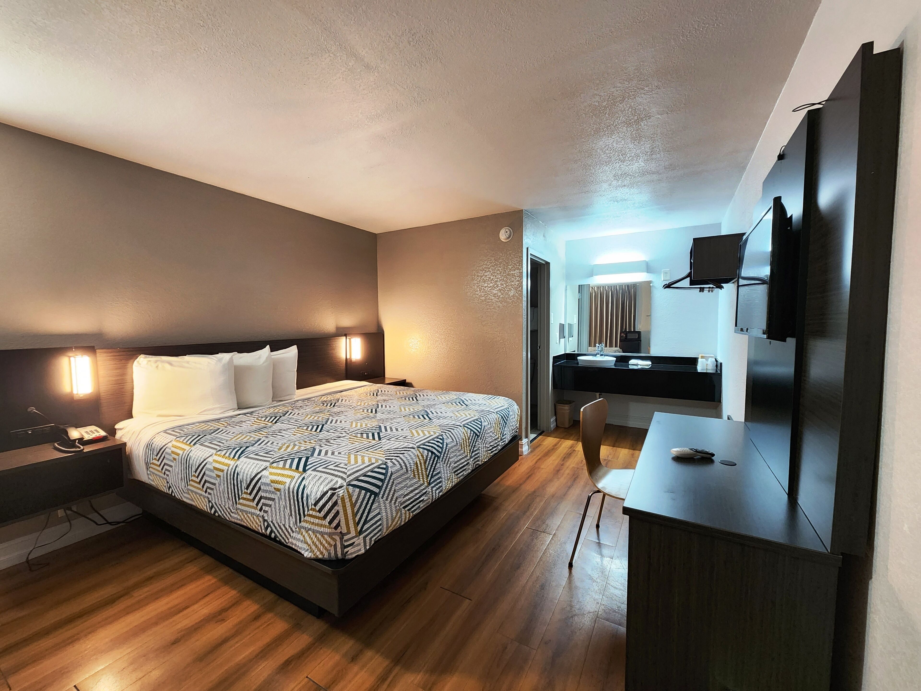 Une chambre d’hôtel moderne avec un grand lit, une table de chevet, une lampe et un bureau avec une chaise.
