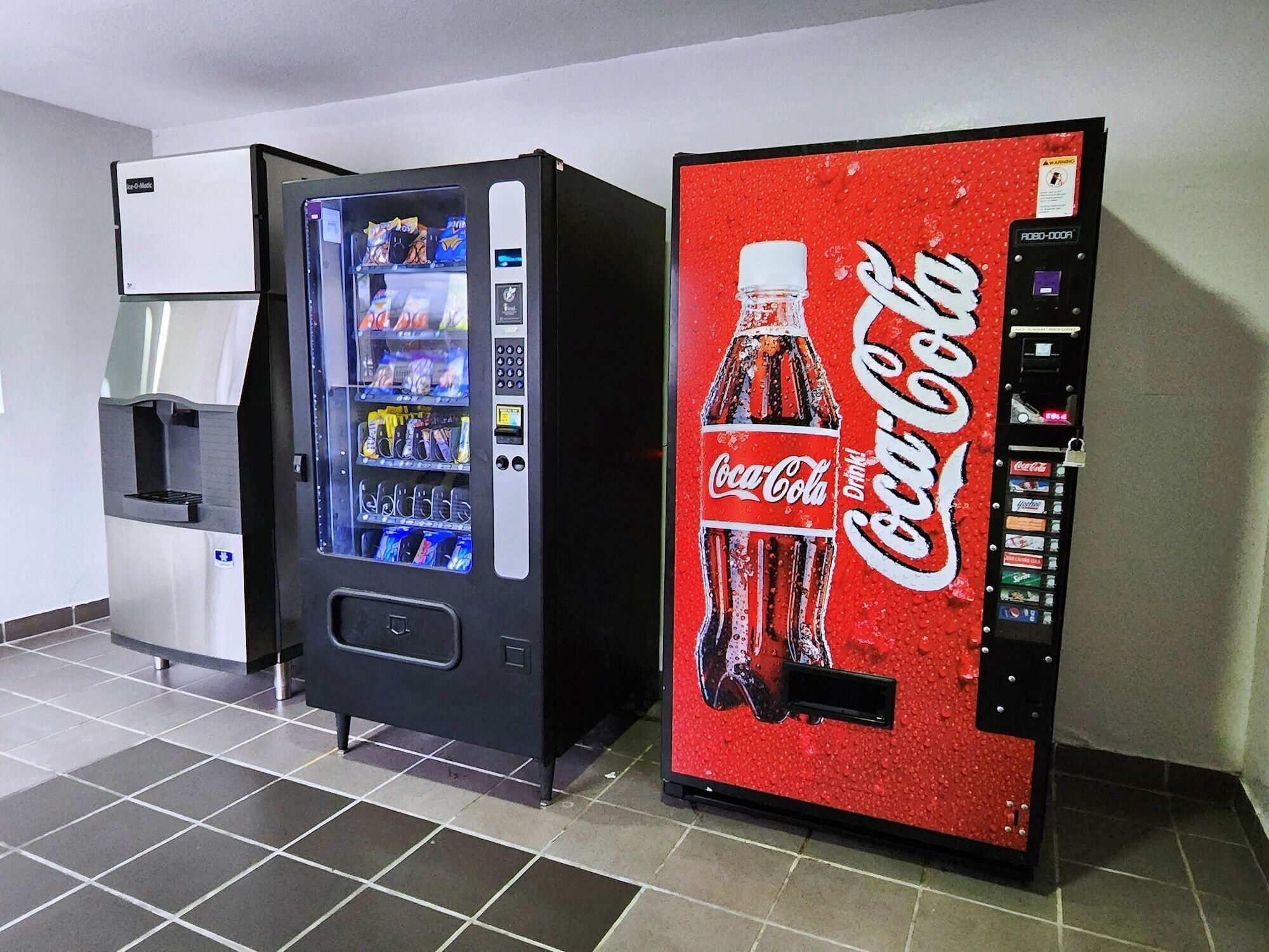 Three vending machines: a water dispenser, a snack vending machine, and a Coca-Cola branded machine.
