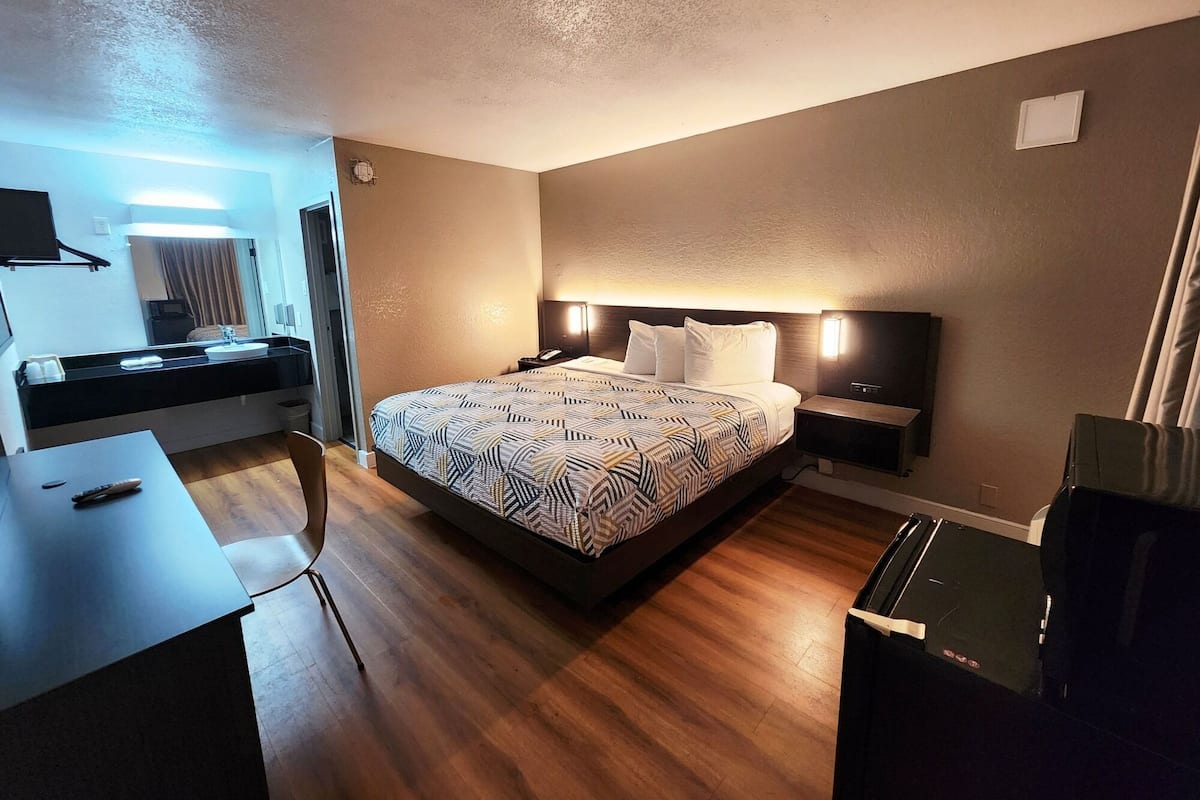A hotel room with a large bed, bedside tables, a desk, and a mirror.