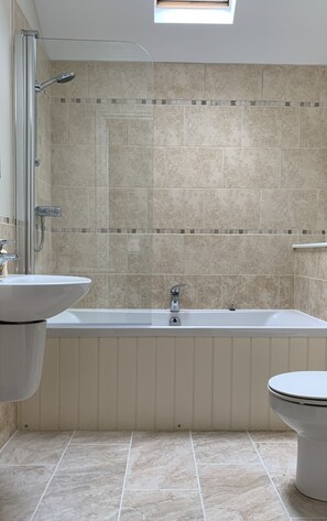 Een bad/douchecombinatie, een haardroger, handdoeken, zeep