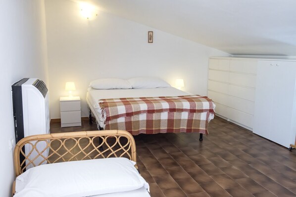 A bedroom with a bed, a bedside table, a lamp, a radiator, and a wardrobe.