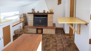 Una cocina con chimenea de ladrillo, armarios de madera y una mesa de madera.