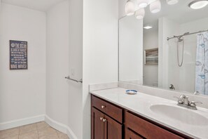 A bathroom with a large mirror, a sink, and a shower. - Sunset Sound: Water Views, Shared Pool, Elevator (Nags Head)