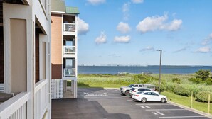 En parkeringsplats med tre bilar, utsikt över havet och en byggnad med en balkong.