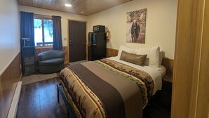 Une chambre avec un lit, un bureau, une chaise, un réfrigérateur et une porte.