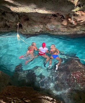 Una piscina natural con agua cristalina, rodeada de formaciones rocosas.