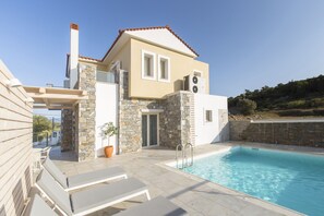 A modern house with a swimming pool, stone walls, and a tiled patio. - Virginia Luxury Villas (Samos)