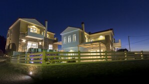 A two-story house with a stone facade, a balcony, and a wooden fence in front. - Virginia Luxury Villas (Samos)