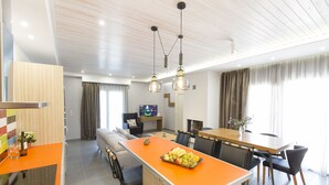 A modern hotel room with a kitchen area, dining space, and a living area. - Virginia Luxury Villas (Samos)