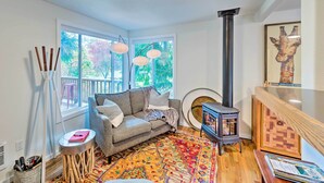 A cozy living room with a sofa, patterned rug, and a wood-burning stove. - House w/ Deck on Whidbey Island, 1 Mi from Shore! (Clinton)
