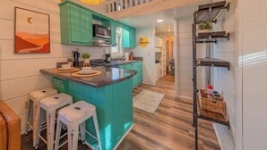 Una cocina con armarios azul verdosos, una isla central y un perchero.