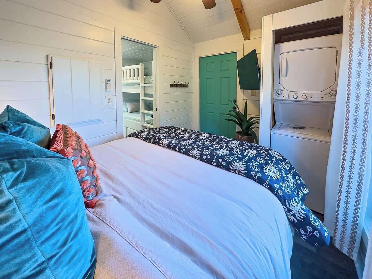 Un dormitorio con literas, lavadora y una puerta verde.