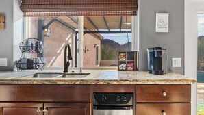 Una cocina con un ventanal grande, una cafetera y un escurreplatos.