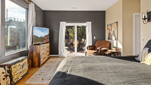 Un dormitorio con una cama grande, un televisor sobre una cómoda de madera, una silla y una mesa con una planta.