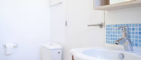 Un baño con inodoro, lavabo y espejo.