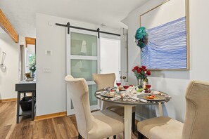 A dining area with a table set for two, chairs, a vase with red roses, and a bottle of wine. - The Nest at Innsbruck| 2 BR| Golf Community and Amenities (Helen)