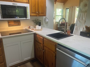 A kitchen with a built-in microwave, a sink, wooden cabinets, and a marble countertop. - Helen Hideaway| 2 BR| Golf Community and Amenities (Helen)