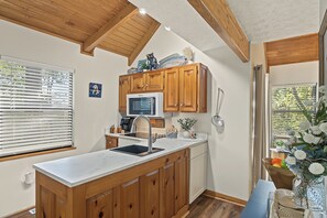 A kitchen with wooden cabinets, a stainless steel sink, and a microwave. - The Nest at Innsbruck| 2 BR| Golf Community and Amenities (Helen)