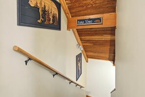 A wooden staircase with a handrail, a bear-themed sign, and a wall-mounted picture of a bear. - The Nest at Innsbruck| 2 BR| Golf Community and Amenities (Helen)