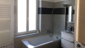 Un baño con bañera, ducha, ventana y espejo.