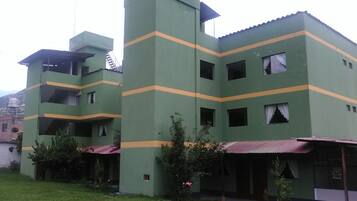 Un edificio de varios pisos con fachada verde y franjas horizontales amarillas.