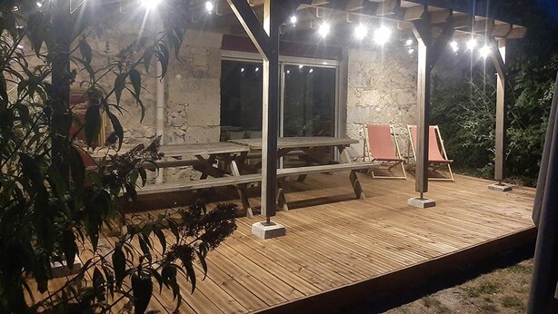 An outdoor wooden deck with a covered seating area, a picnic table, and two lounge chairs. - Le Ténarèze, bed and breakfast for a large tribe (CONDOM)