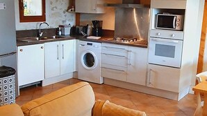 A compact kitchen with a washing machine, microwave, and oven. - Le Ténarèze, bed and breakfast for a large tribe (CONDOM)