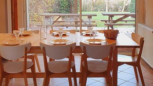 A dining area with a table set for four, large windows, and a view of the outdoors. - Le Ténarèze, bed and breakfast for a large tribe (CONDOM)