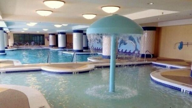 Ein Hallenbad mit mehreren Bahnen, einer zentralen Wasserspende und Fliesenboden.