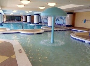 Una piscina interior con varias pistas de natación, una fuente central y suelo de baldosas.