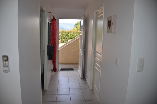 Un couloir donnant sur un balcon et des montagnes.