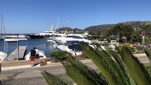 Una marina con diversi yacht ormeggiati, una persona che passeggia con un cane e un cartello con scritto 'San Juan'.