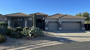 Una casa de dos pisos amb garatge, carril d'accés i un jardí de cactus.