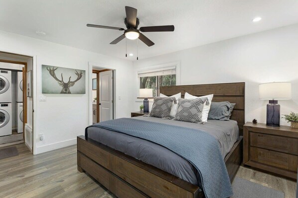 A bedroom with a bed, a ceiling fan, a nightstand, a lamp, and a wall-mounted TV.