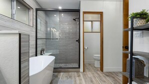 Une salle de bain moderne avec une douche à parois de verre, une baignoire blanche et des toilettes.