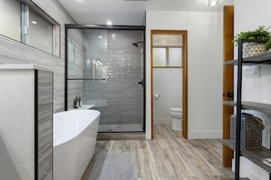 Een moderne badkamer met een douchecabine van glas, een witte badkuip en een toilet.